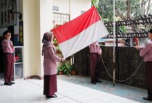 Guru SD Muhammadiyah PK Solo membentangkan bendera Merah Putih saat bertugas sebagai pengibar bendera dalam upacara HUT ke-81 RI