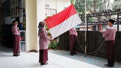 Guru SD Muhammadiyah PK Solo membentangkan bendera Merah Putih saat bertugas sebagai pengibar bendera dalam upacara HUT ke-81 RI