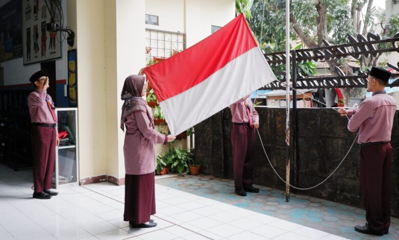 Guru SD Muhammadiyah PK Solo membentangkan bendera Merah Putih saat bertugas sebagai pengibar bendera dalam upacara HUT ke-81 RI