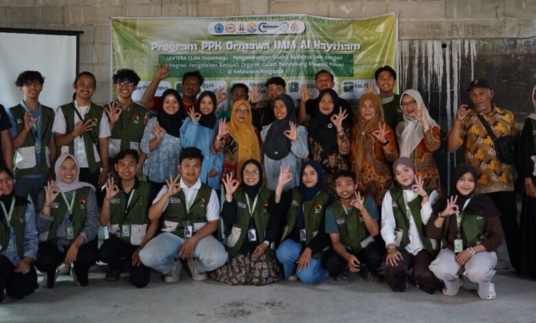Foto bersama tim mahasiswa PPK Ormawa Unimus dan warga Pringapus dalam kegiatan pelatihan pemasaran digital produk, berpose membentuk tanda 'OK' di depan spanduk acara di dalam ruangan.