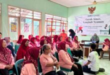 Suasana penyuluhan kesehatan dan skrining keseimbangan lansia oleh Tim Fisioterapis UMS di Puskesmas Mojolaban. Puluhan ibu lansia tampak duduk menyimak materi dengan spanduk bertuliskan 'Gerak Aman, Langkah Nyaman' di latar belakang.