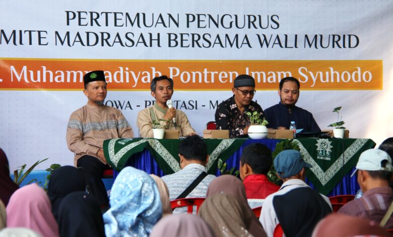 Empat pejabat madrasah duduk di panggung di belakang spanduk untuk rapat wali murid MTs Muhammadiyah Pontren Imam Syuhodo.