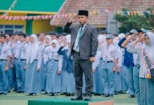 Bapak Wasi’un memimpin upacara dengan sikap hormat di depan barisan siswa pada momen pembukaan SPMB SMK Mutual 2027/2028.