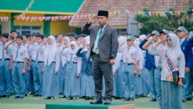 Bapak Wasi’un memimpin upacara dengan sikap hormat di depan barisan siswa pada momen pembukaan SPMB SMK Mutual 2027/2028.