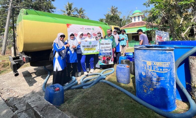 Tim relawan SMA MUH1 Cilacap foto bersama truk tangki saat penyaluran bantuan air bersih Cilacap untuk warga terdampak kekeringan.