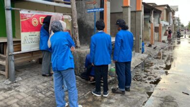 Mahasiswa PPK ORMAWA UNIMUS jas biru memasang plang penunjuk arah Lokasi Desa Wisata Lentera Tambak Lorok Semarang