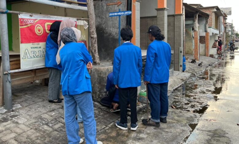 Mahasiswa PPK ORMAWA UNIMUS jas biru memasang plang penunjuk arah Lokasi Desa Wisata Lentera Tambak Lorok Semarang