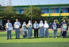 Siswa dan guru SMK Mutual Magelang foto bersama memegang piala dan sertifikat prestasi MAPSI SMK Kota Magelang 2026 di lapangan sekolah.