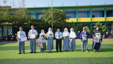 Siswa dan guru SMK Mutual Magelang foto bersama memegang piala dan sertifikat prestasi MAPSI SMK Kota Magelang 2026 di lapangan sekolah.