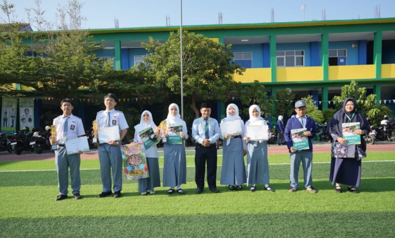 Siswa dan guru SMK Mutual Magelang foto bersama memegang piala dan sertifikat prestasi MAPSI SMK Kota Magelang 2026 di lapangan sekolah.