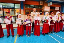 Siswa dan siswi SD Muhammadiyah 1 Ketelan Surakarta berdiri berjejer memegang piala dan sertifikat penghargaan didampingi pembina upacara.