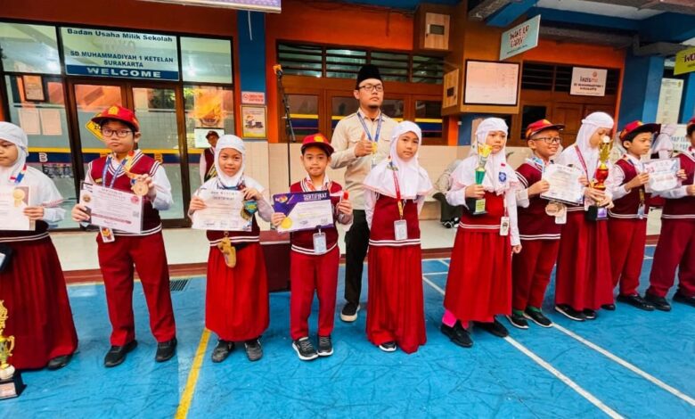Siswa dan siswi SD Muhammadiyah 1 Ketelan Surakarta berdiri berjejer memegang piala dan sertifikat penghargaan didampingi pembina upacara.