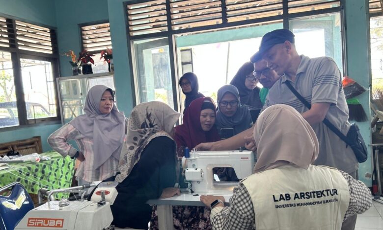Sekelompok orang sedang mengerumuni sebuah mesin jahit di dalam sebuah ruangan bengkel, mendengarkan penjelasan dari seorang instruktur tentang cara mengoperasikannya dalam rangka pelatihan produksi batik ciprat.
