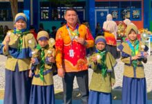 Kepala sekolah bersama guru dan siswa SD Bilingual Muhammadiyah 1 Purwodadi memamerkan medali serta piala kejuaraan Olimpiade Airlangga dan Got Talent di halaman sekolah.