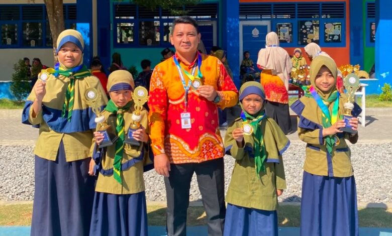 Kepala sekolah bersama guru dan siswa SD Bilingual Muhammadiyah 1 Purwodadi memamerkan medali serta piala kejuaraan Olimpiade Airlangga dan Got Talent di halaman sekolah.