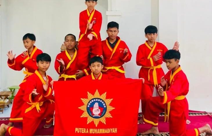 Delapan santri pesilat Tapak Suci Ponpes Nurul Ilmi Bucu Jepara berseragam merah memasang kuda-kuda beladiri sambil membentangkan bendera Putera Muhammadiyah.