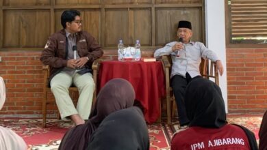 Sastrawan Ahmad Tohari mengenakan kemeja putih dan peci hitam sedang berbicara memegang mikrofon di depan peserta Kelas Literasi IPM Banyumas.