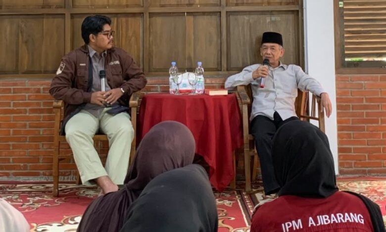 Sastrawan Ahmad Tohari mengenakan kemeja putih dan peci hitam sedang berbicara memegang mikrofon di depan peserta Kelas Literasi IPM Banyumas.