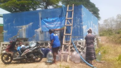 Tim LAZISMU At-Tajdid mendistribusikan bantuan air bersih ke penampungan warga Dusun Pasarsore Blora menggunakan selang dan galon.