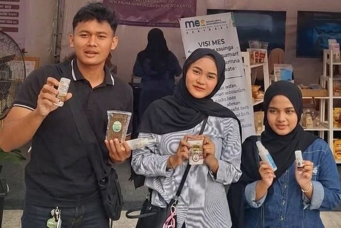Tiga mahasiswa anggota GenBI memperlihatkan produk inovasi riset dosen UMP di pameran SELARAS 2026.