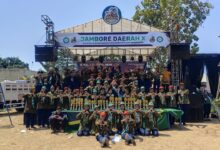 Sekelompok besar kader Hizbul Wathan berfoto bersama di depan panggung utama Jambore Daerah ke-X Kwarda Pemalang dengan barisan piala di depan mereka.