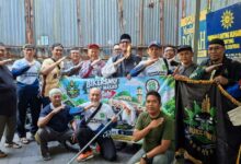 Anggota Komunitas BikersMu Surabaya dan GowesMu Surabaya berfoto bersama membentangkan spanduk aksi bersih-bersih masjid di depan Masjid Da'wah Blauran.