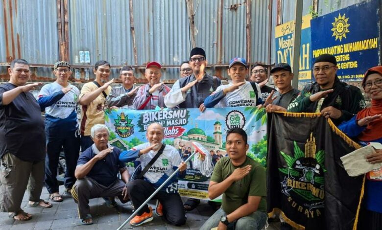 Anggota Komunitas BikersMu Surabaya dan GowesMu Surabaya berfoto bersama membentangkan spanduk aksi bersih-bersih masjid di depan Masjid Da'wah Blauran.