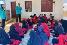 Dua mahasiswa UMS mengenakan almamater hijau memberikan edukasi cegah dampaknya bullying pada anak kepada siswa SDN 01 Wonotoro di Desa Catur Boyolali.