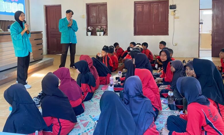 Dua mahasiswa UMS mengenakan almamater hijau memberikan edukasi cegah dampaknya bullying pada anak kepada siswa SDN 01 Wonotoro di Desa Catur Boyolali.
