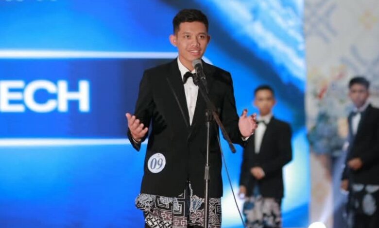 Ghufron Zachri mahasiswa AKMT mengenakan jas hitam dan kain batik sedang berbicara di depan mikrofon saat Grand Final Duta GenRe Temanggung 2026