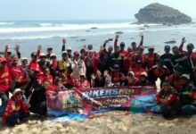 Anggota BikersMu Chapter Kota Yogyakarta berfoto bersama membentangkan spanduk di tepi Pantai Watu Karung Pacitan.