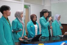Lima mahasiswa pengembang platform BenerinAja UMS KMI Expo 2026 mengenakan jas almamater hijau tosra sedang melakukan presentasi di depan laptop dan meja ruangan.