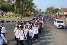 Rombongan mahasiswa baru mengenakan kaos putih berbaris dalam kegiatan Pawai Taaruf UMPWR 2026 di jalanan Kota Purworejo.