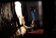 Foto dalang cilik Aditya Ghandi sedang memegang gunungan wayang kulit di depan layar putih bercahaya, dalam rangkaian acara Milad ke-68 FKIP UMS.