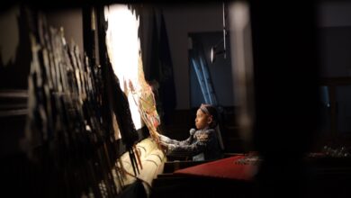 Foto dalang cilik Aditya Ghandi sedang memegang gunungan wayang kulit di depan layar putih bercahaya, dalam rangkaian acara Milad ke-68 FKIP UMS.