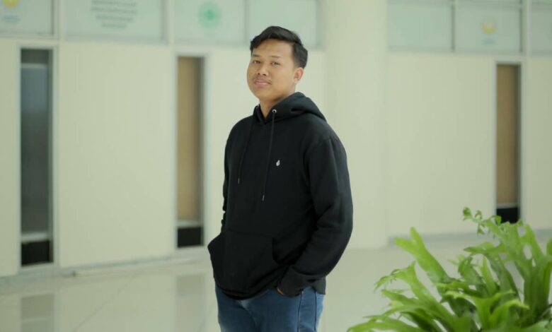 Muhammad Farhan, mahasiswa UMS pemenang Juara 1 lomba review Film Pangku Tempo, berpose mengenakan hoodie hitam di koridor kampus UMS.