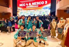 Tim Sang Surya UMS berpose di panggung penghargaan NCC 4 di Bali, memegang tiga sertifikat penghargaan untuk Favorite Poster, Silver Medal, dan Bronze Medal di depan latar panggung merah.