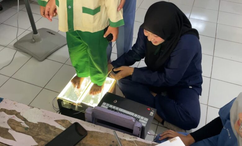 Mahasiswa Fisioterapi UMS mengoperasikan alat deteksi lengkung kaki anak berbasis IoT yang sedang diuji coba oleh seorang anak TK.