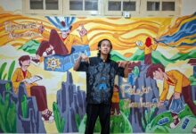 Wildan berdiri di depan mural karya PD IPM Temanggung berjudul Migunani di Era Digital di Kantor PP IPM Yogyakarta.