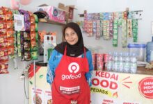 Fina Herlinawati mahasiswi Teknik Sipil UMP berdiri di kios usahanya menjelang wisuda.