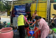 Warga mengantre dan mengisikan bantuan air bersih Grobogan dari truk tangki SMA Muhammadiyah Purwodadi ke dalam drum dan jeriken.