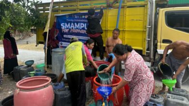 Warga mengantre dan mengisikan bantuan air bersih Grobogan dari truk tangki SMA Muhammadiyah Purwodadi ke dalam drum dan jeriken.