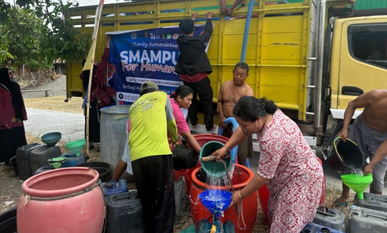 Warga mengantre dan mengisikan bantuan air bersih Grobogan dari truk tangki SMA Muhammadiyah Purwodadi ke dalam drum dan jeriken.