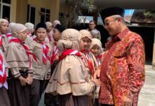 Mendikdasmen Abdul Mu'ti tersenyum dan bersalaman dengan siswa sekolah Muhammadiyah berseragam pramuka di Malang