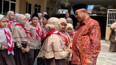Mendikdasmen Abdul Mu'ti tersenyum dan bersalaman dengan siswa sekolah Muhammadiyah berseragam pramuka di Malang