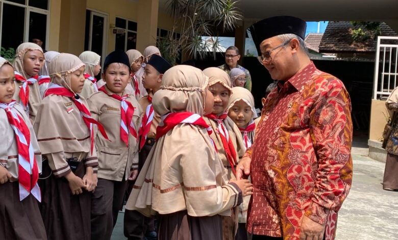 Mendikdasmen Abdul Mu'ti tersenyum dan bersalaman dengan siswa sekolah Muhammadiyah berseragam pramuka di Malang