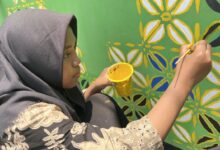 Siswi SMP Muliya Kalinyamatan Jepara sedang melukis mural motif batik Muhammadiyah di dinding sekolah memperingati Hari Batik Nasional.