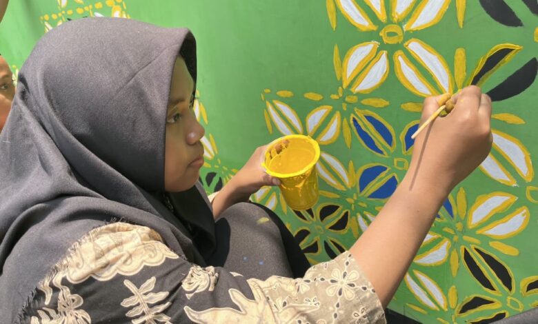 Siswi SMP Muliya Kalinyamatan Jepara sedang melukis mural motif batik Muhammadiyah di dinding sekolah memperingati Hari Batik Nasional.
