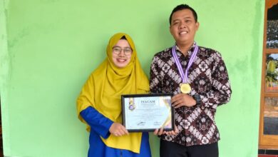 Dosen UNIMUS Prima Trisna Aji memegang piagam penghargaan Juara 1 Lomba Abstrak Nasional dan mengenakan medali bersama seorang wanita.