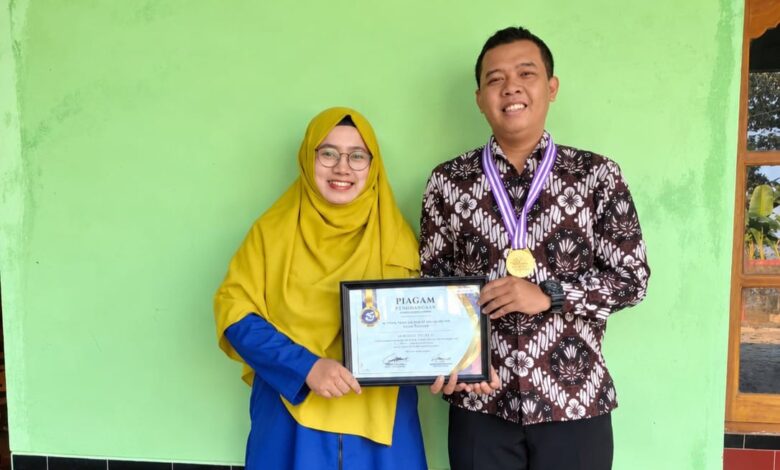 Dosen UNIMUS Prima Trisna Aji memegang piagam penghargaan Juara 1 Lomba Abstrak Nasional dan mengenakan medali bersama seorang wanita.